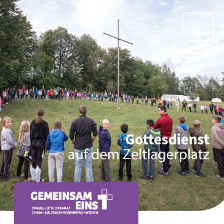 Kinder stehen im Kreis um ein Kreuz